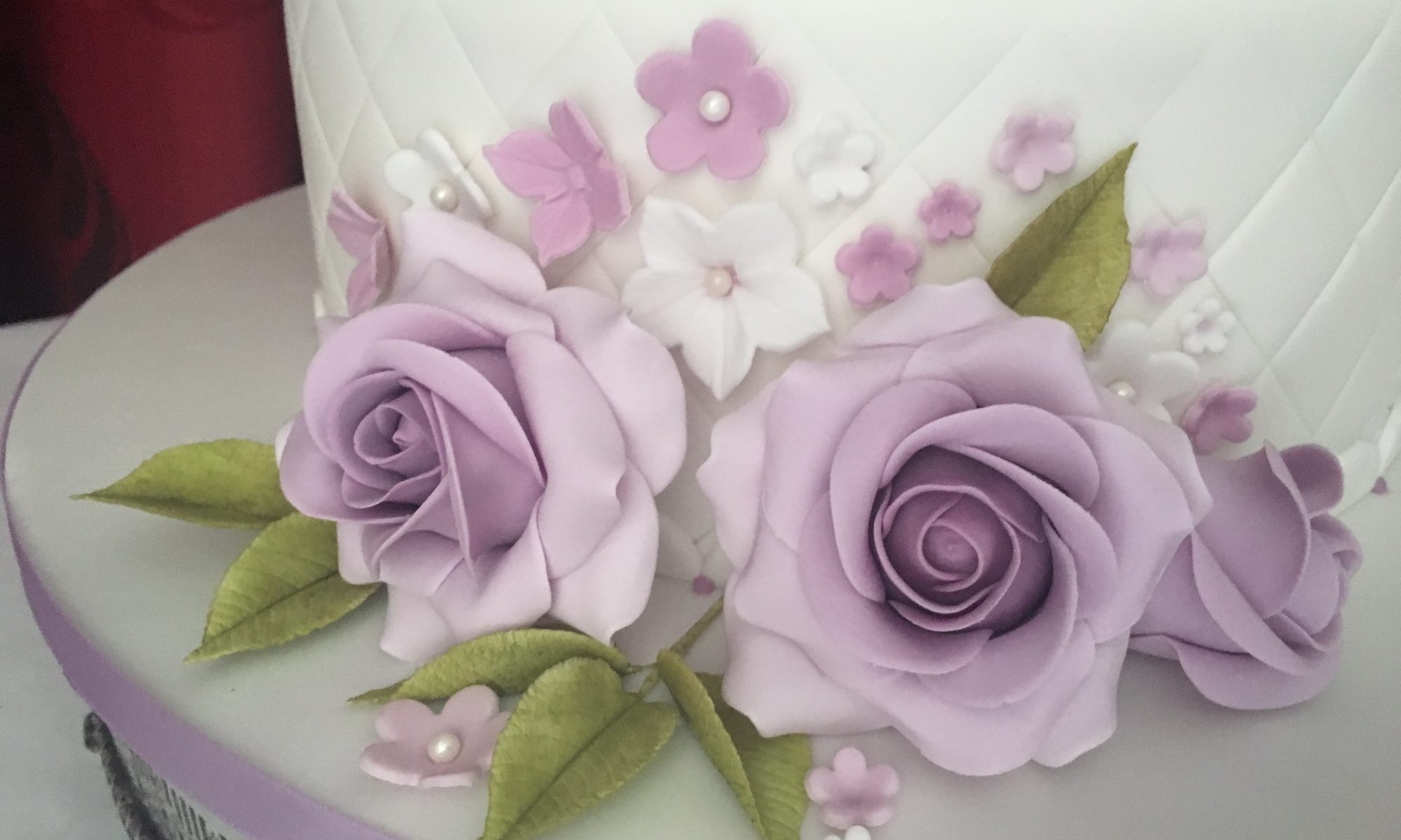 Close-up of handmade lilac sugar roses on a quilted cake