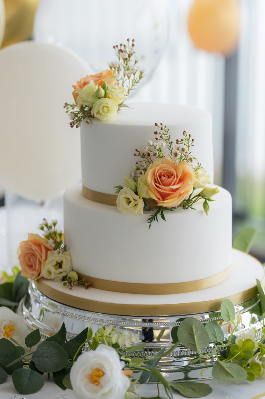 White wedding cake with peach roses and greenery